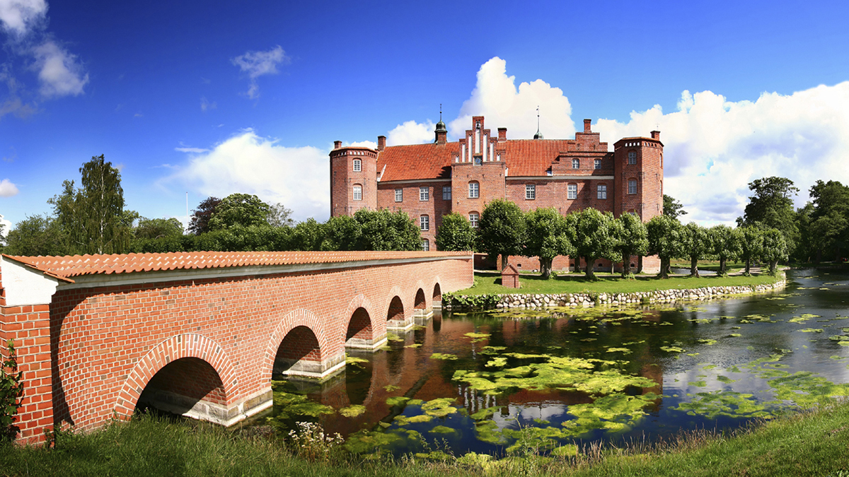 Castle or large manor house in Denmark. Gammel Estrup castle seen from front with moat and bridge